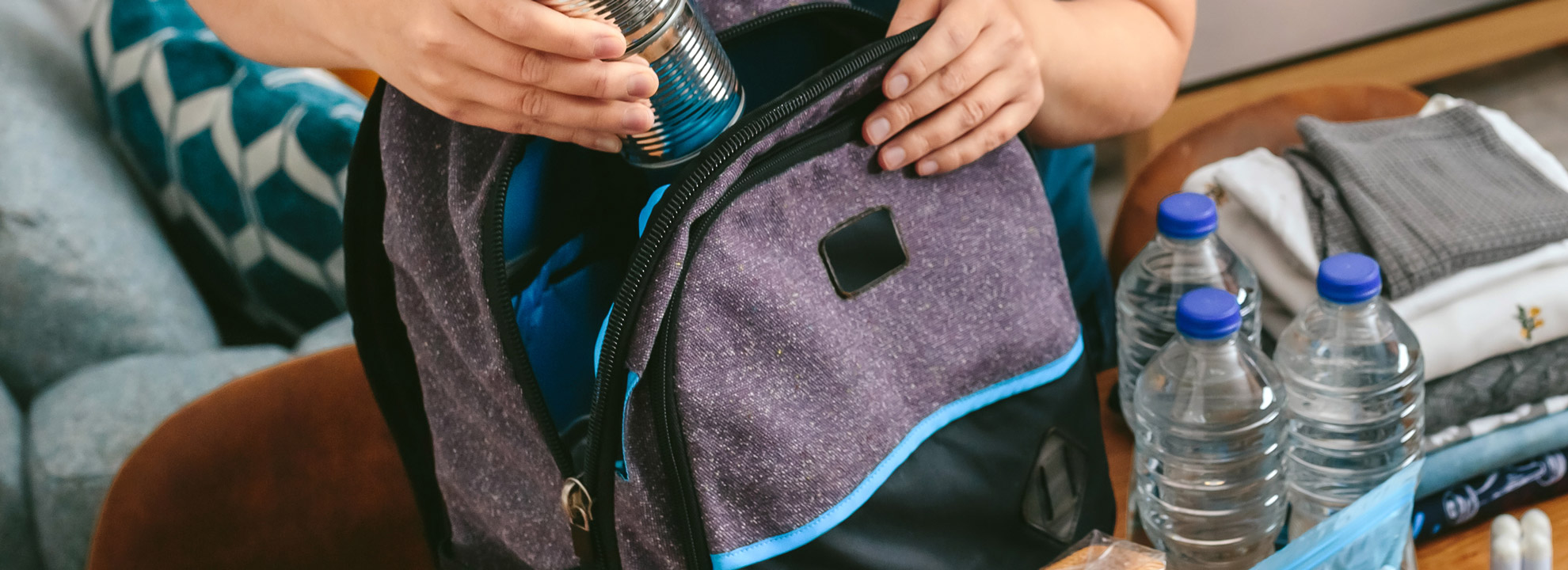 Image of a woman's hands packing essentials into a backpack.