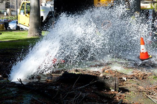 Water gushing from the ground into the air as a result of a water main burst.