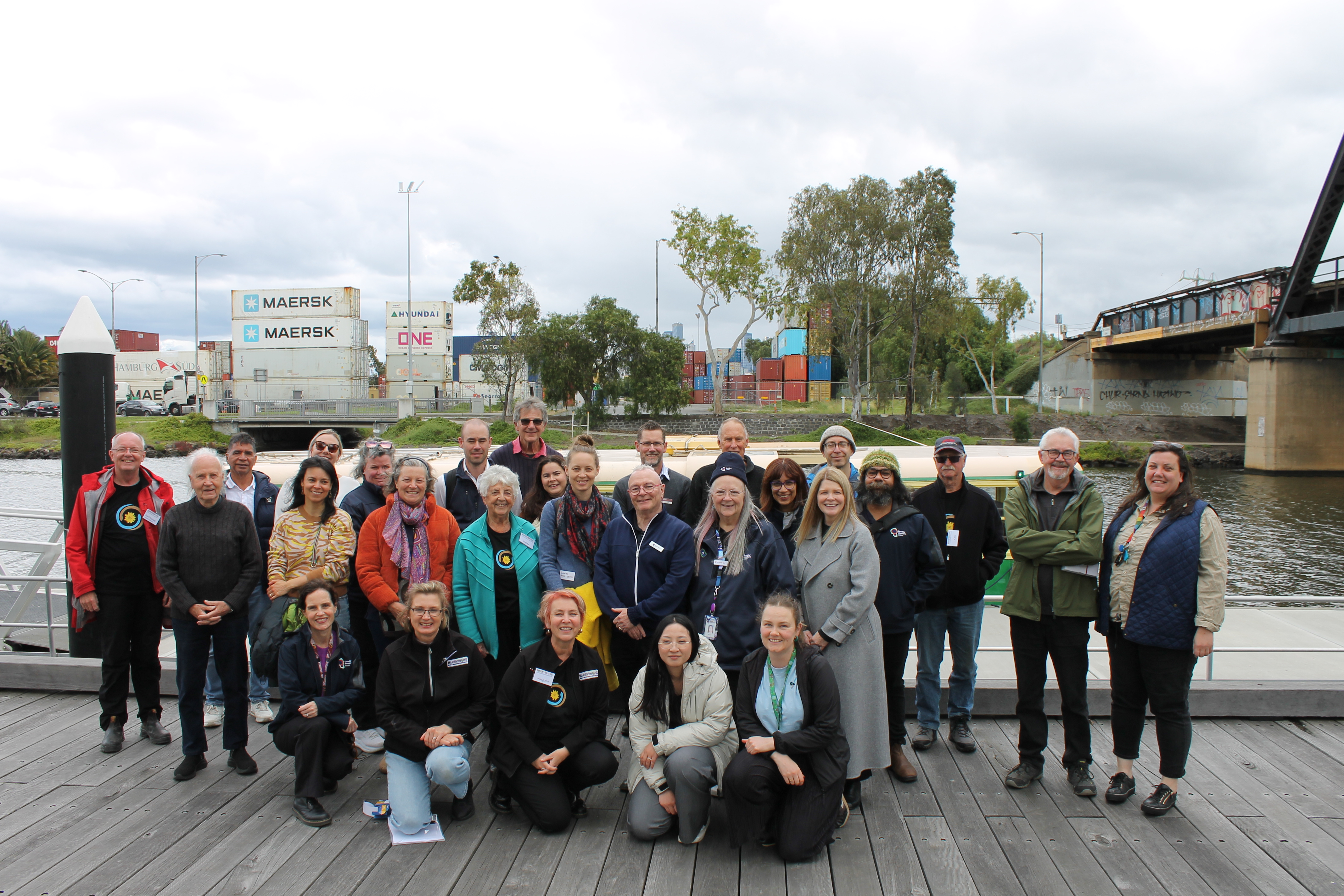 Group of people standing on a dock in front of a tramboat 