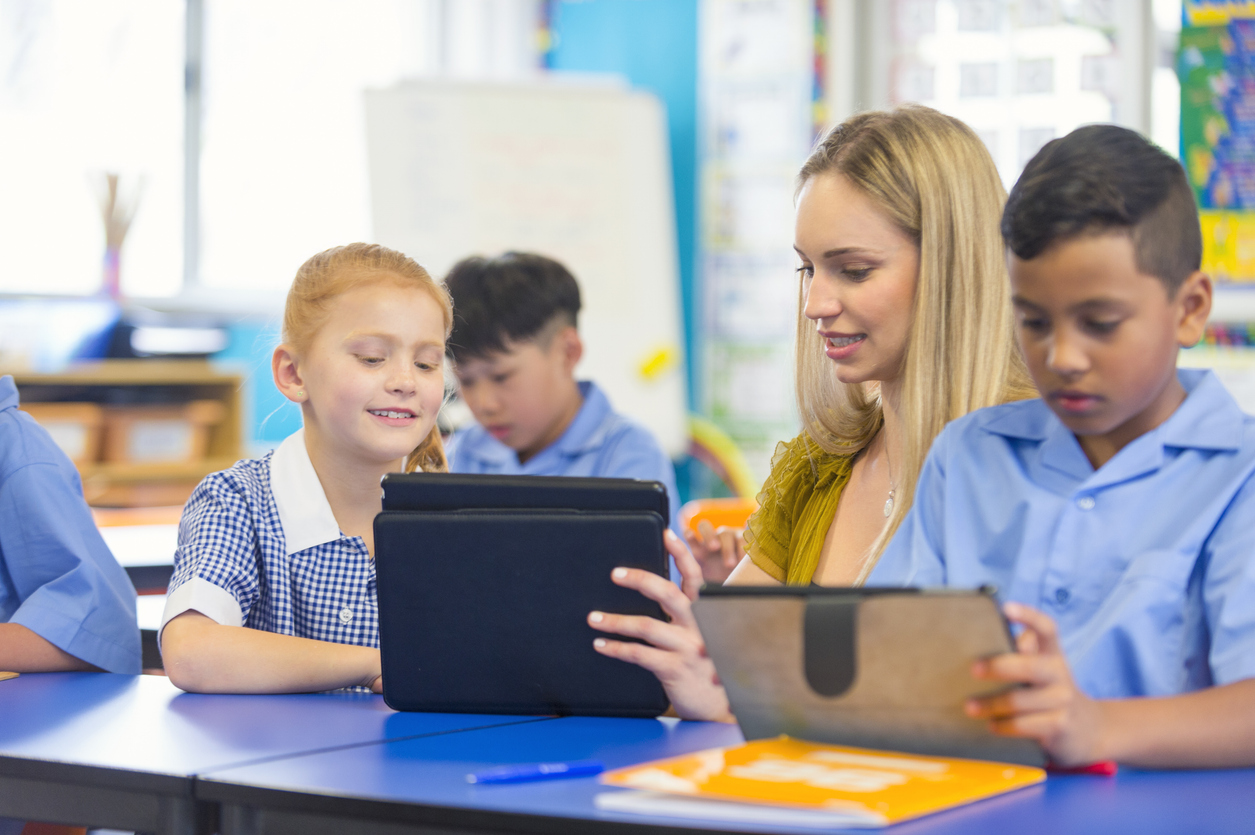 Classroom scene with teachers and pupils looking at ipads/tablets