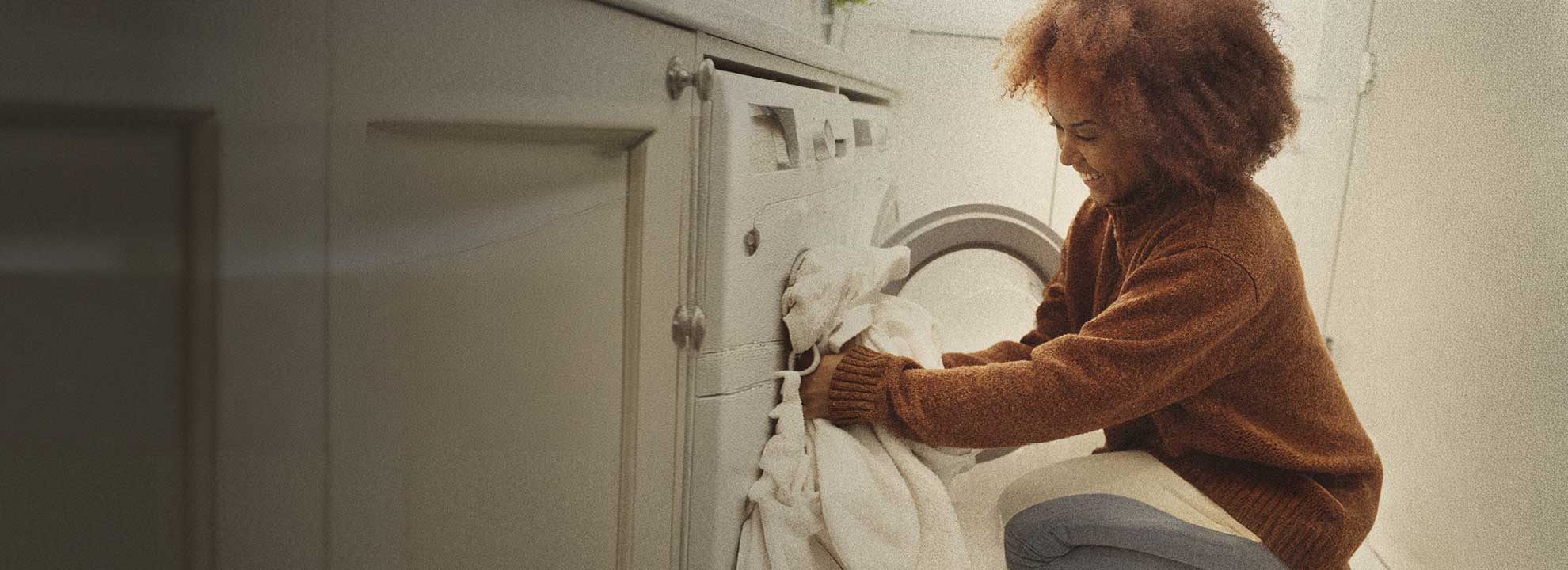 A dimly lit image of a person removing washing from their washing machine