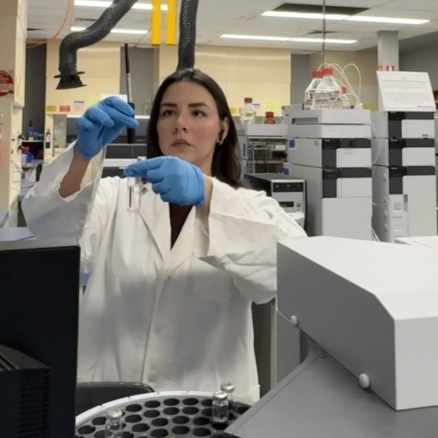 Laryssa in a lab environment holding a test tube 