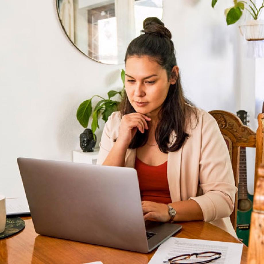 A woman sitting at a table looking at a laptop computer
