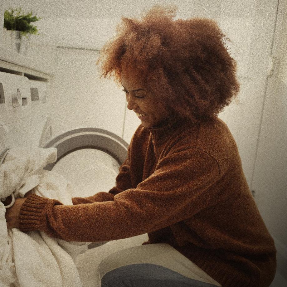 Person putting sheet into washing machine 