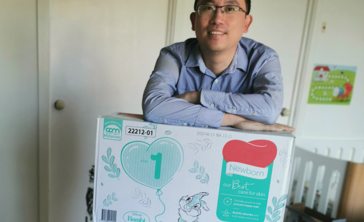 Photo of GWW staff member at home with a box of nappies