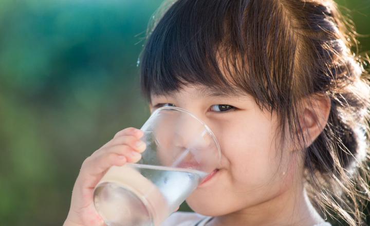 A young girl drinking a glass of water