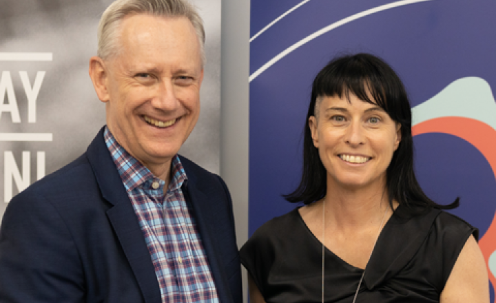 Image of Adam Shoemaker and Maree Lang standing in front of a VU banner and a GWW banner holding MOU
