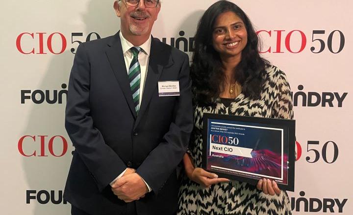 Two people stand and smile at an awards night.