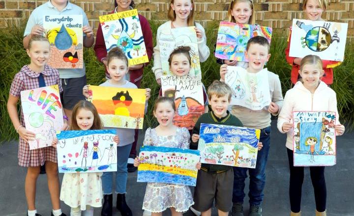 A group of 13 school children pose with their handmade posters. 