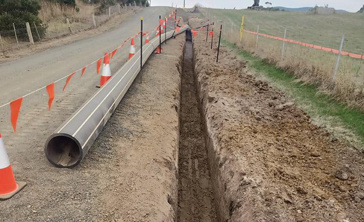 A new sewer pipe lies next to long trench. 