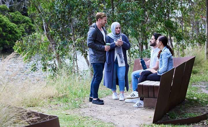 A group of four people talking in a park.