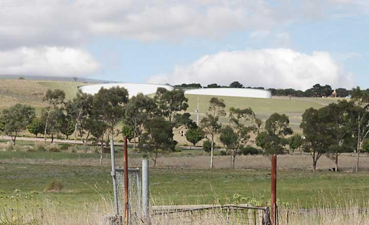 An artist's impression of the water tanks being constructed on Bald Hill in Sunbury. Two large tanks in the distance and surrounded by trees and bushes.