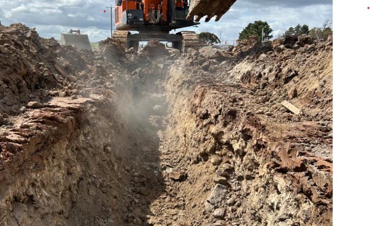 An industrial digger digs a trench for a new water main.