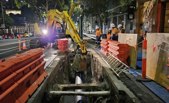A new water pipe is installed in a bust street at night. 