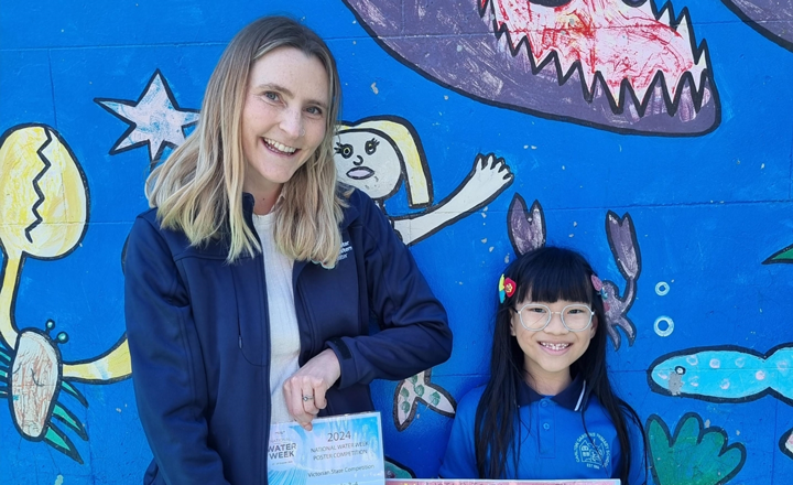 A woman standing with a young girl holding a certificate