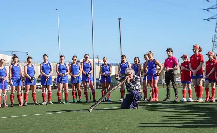 Players and coaches from the Footscray Hockey Club watching a local Elder conduct a Welcome to Country Smoking Ceremony.