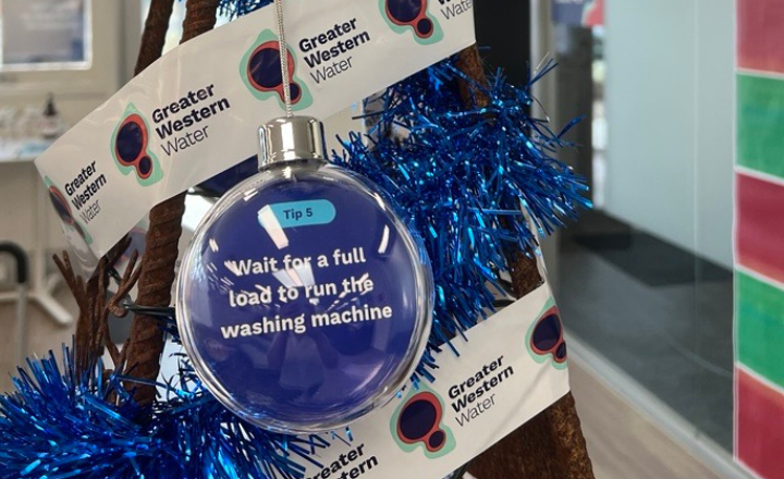 A tree made from a metal frame with blue tinsel, baubles and a message to run your washing machine on a full load