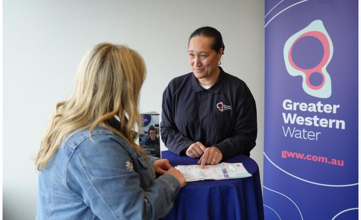 A GWW representative speaking with a customer, a branded banner in the background