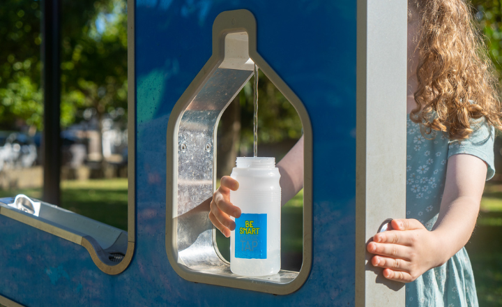 A young girl filling up a water bottle at a water fountain
