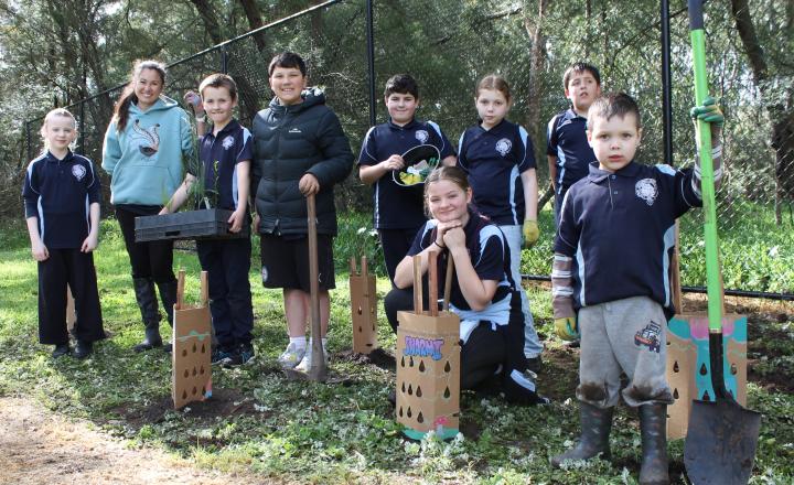 A teacher and students standing by the tube trees they planted.