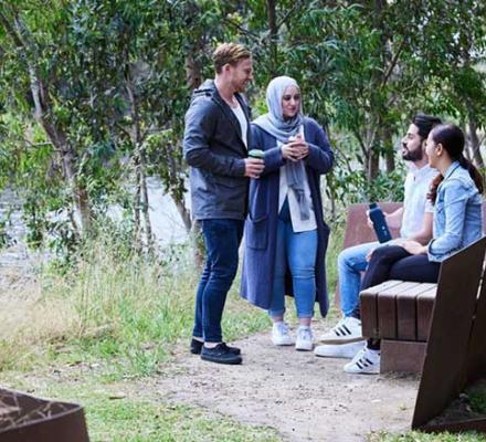 A group of four people talking in a park.