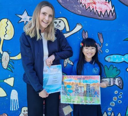 A woman standing with a young girl holding a colourful poster.