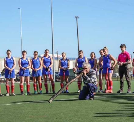 Players and coaches from the Footscray Hockey Club watching a local Elder conduct a Welcome to Country Smoking Ceremony.