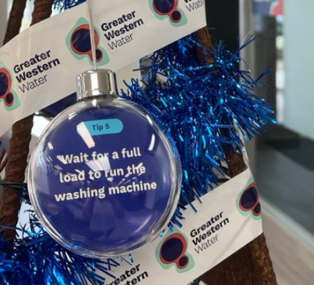 A tree made from a metal frame with blue tinsel, baubles and a message to run your washing machine on a full load