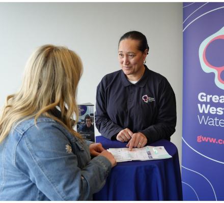 A GWW representative speaking with a customer, a branded banner in the background