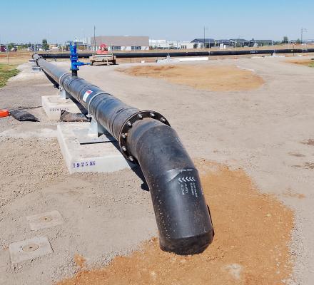 A long black pipe, approximately 45cm in diameter, resting on concrete stands.
